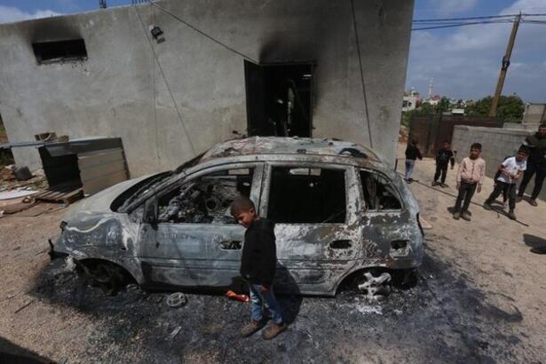 En palestinsk gutt foran en &oslash;delagt bil